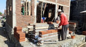 Tukang bangunan profesional Patrialand sedang bekerja memasang keramik di proyek rumah Blitar.