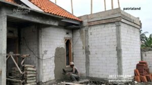 Tukang bangunan sedang melakukan proses plesteran semen pada dinding luar hebel untuk mencegah kebocoran dan rembes air.