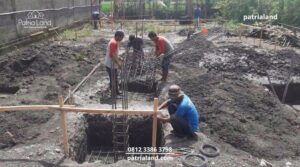 Rakitan besi tulangan pondasi cakar ayam dan tiang kolom yang dipasang di dalam galian tanah untuk memastikan struktur rumah dua lantai kuat dan kokoh.