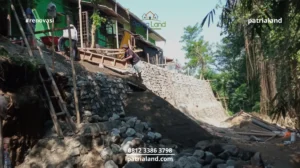Proses pengerjaan pembuatan talud penahan tanah menggunakan material batu kali kokoh oleh pekerja konstruksi profesional Patrialand.