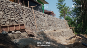 Pemasangan pipa drainase atau weep hole pada struktur pondasi talud penahan tanah untuk membuang tekanan air dan mencegah longsor.