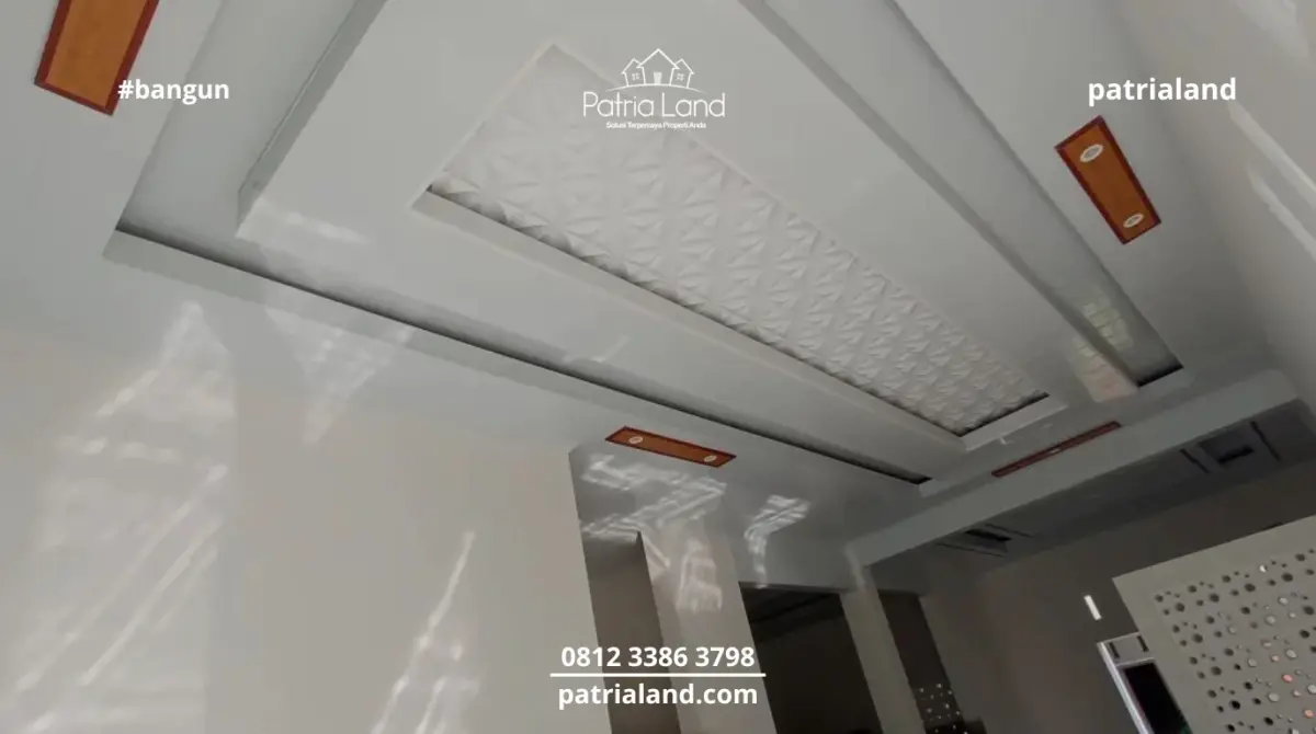 Interior mewah dengan plafon PVC drop ceiling motif 3D dan aksen kayu, ditambah pantulan cahaya alami dari desain roster.