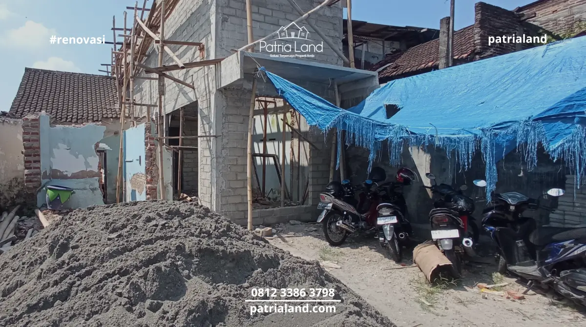 Persiapan material pasir dan pembongkaran sebagian dinding pada tahap awal perombakan rumah lama menjadi hunian kos multi-kamar.