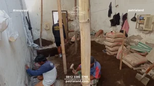 Tim pekerja konstruksi sedang melakukan pengukuran presisi dan penataan ulang tata ruang interior untuk pembagian kamar kos