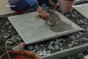 Tukang jasa renovasi rumah Blitar sedang memperbaiki keramik lantai terangkat menggunakan semen perekat khusus.
