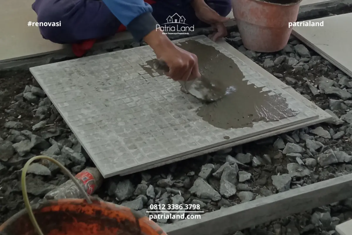 Tukang jasa renovasi rumah Blitar sedang memperbaiki keramik lantai terangkat menggunakan semen perekat khusus.