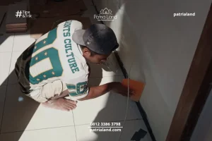 Pekerja Patria Land melakukan cara plamir tembok yang benar dengan kape untuk hasil finishing rumah yang rata.