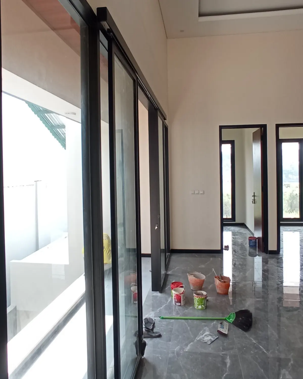 Pintu geser kaca lebar yang difungsikan sebagai partisi ruangan fleksibel tanpa mengorbankan kesan lapang pada interior rumah.