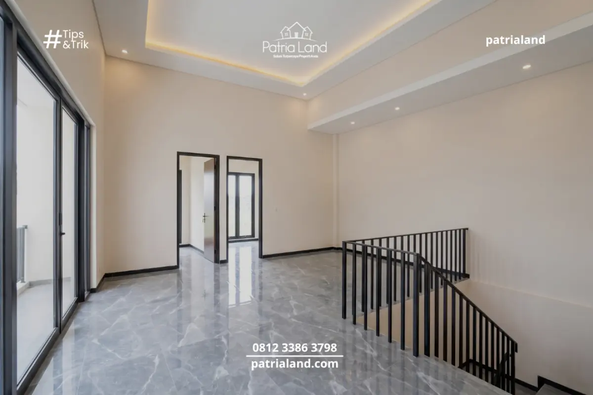 Lantai granit abu-abu yang digunakan di seluruh area ruang keluarga, memberikan kesan netral yang mudah dipadukan dengan furnitur dan partisi kaca aluminium hitam.